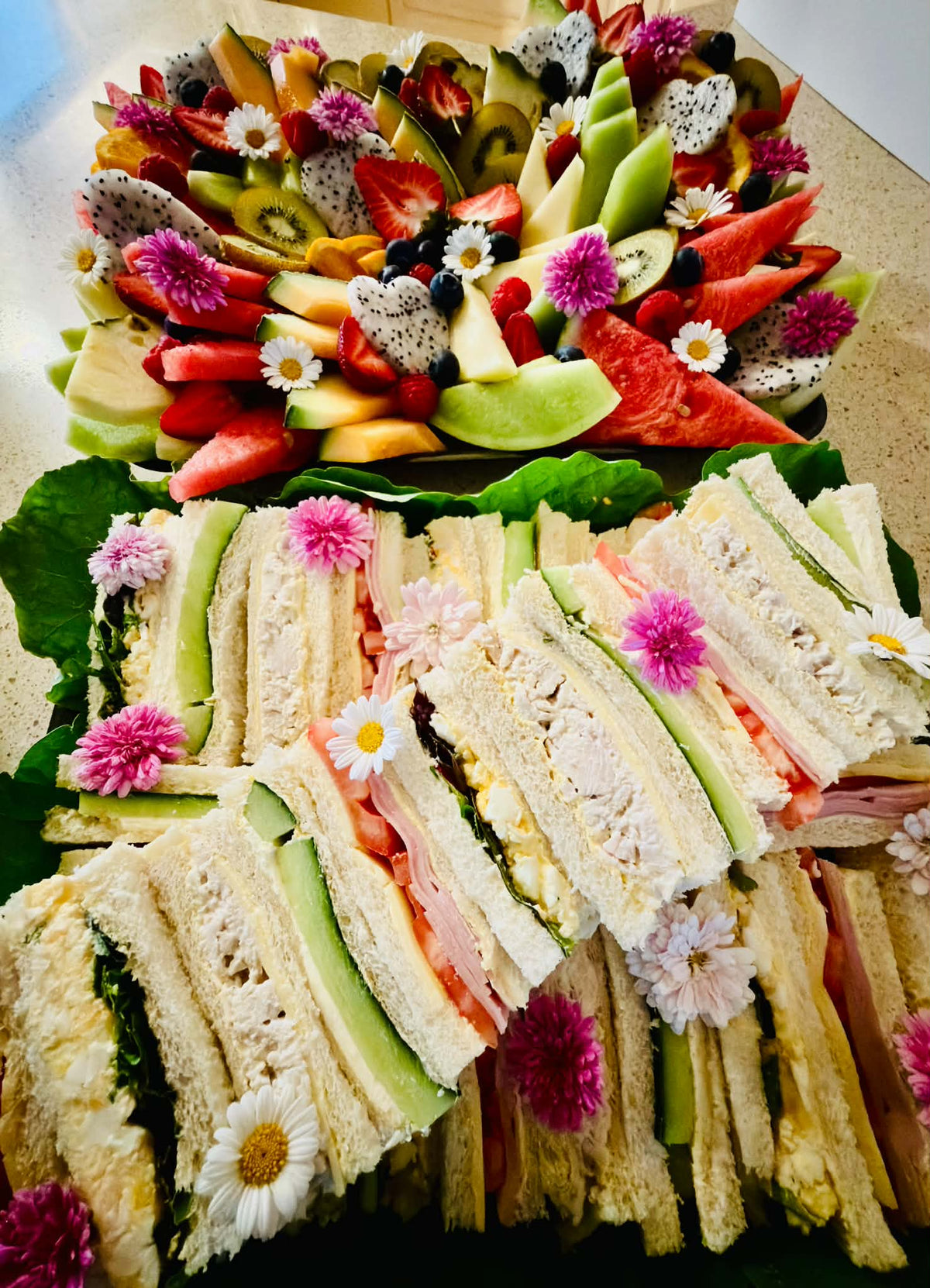 Gourmet finger sandwiches presented with a fresh fruit platter